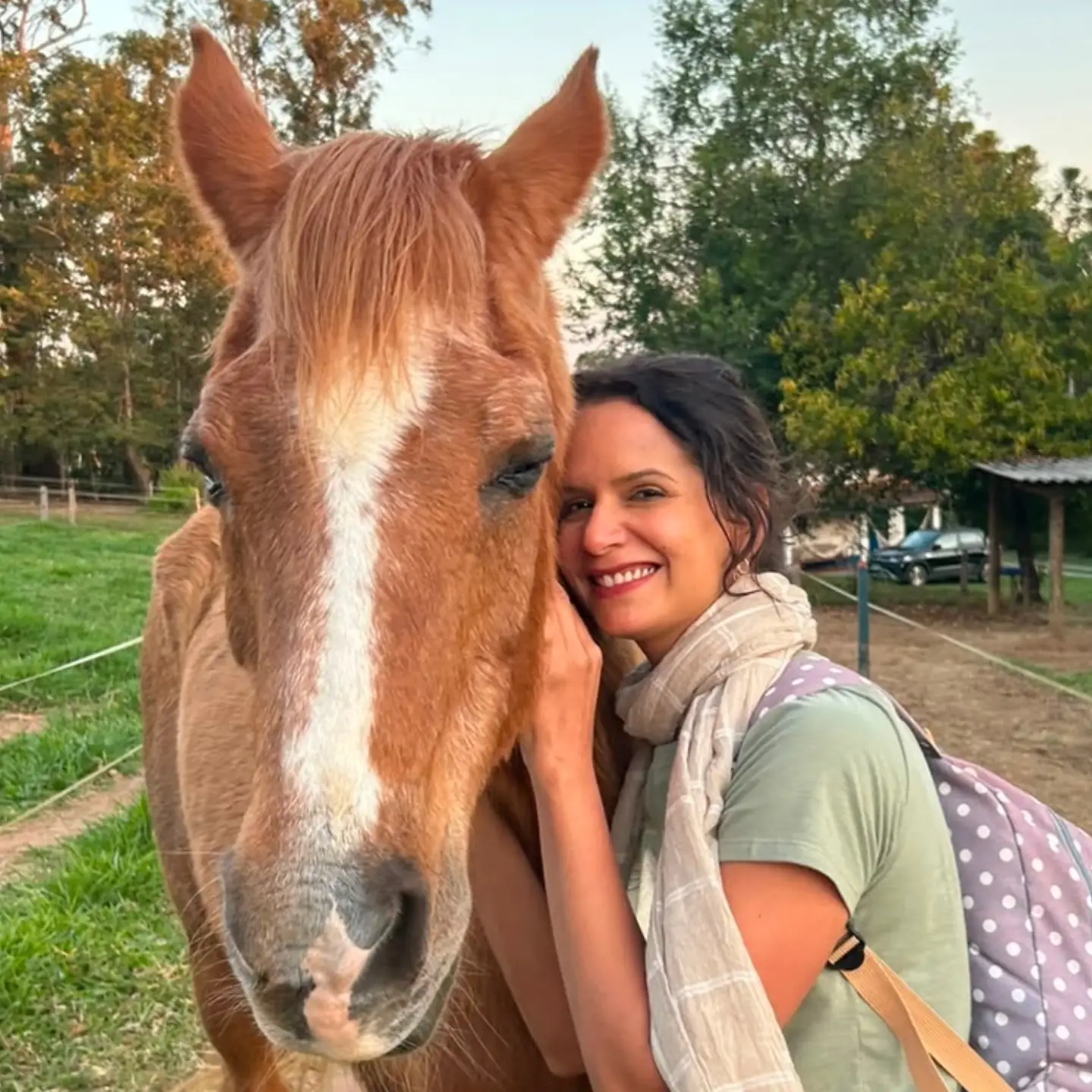Dra. Cirleine Couto abraçada ao cavalo em ambiente de haras durante prática de equoterapia
